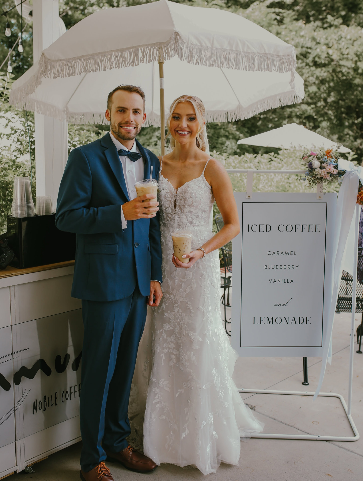 A couple holding iced coffees in front of the Commune coffee cart